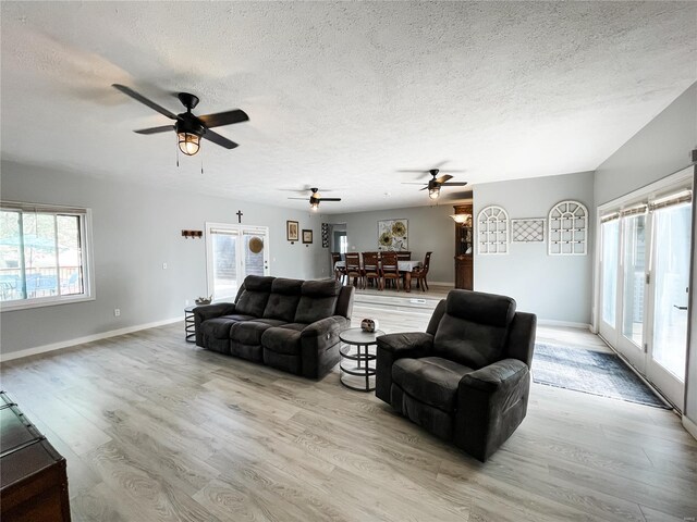 living room with baseboards, a ceiling fan, wood finished floors, and a textured ceiling