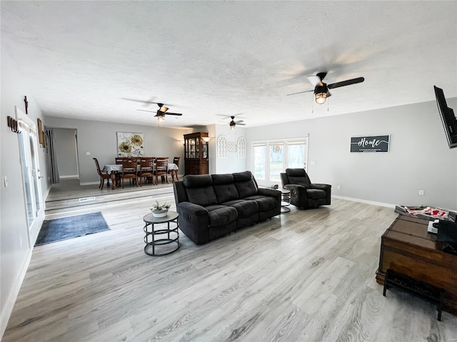 living area featuring baseboards, wood finished floors, a textured ceiling, and ceiling fan