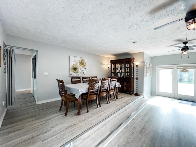 dining room with baseboards, wood finished floors, a textured ceiling, and ceiling fan