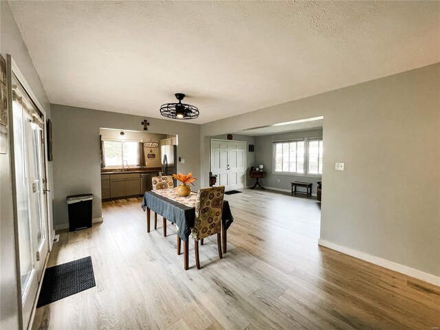 dining area with baseboards, a textured ceiling, light wood-style floors, and ceiling fan