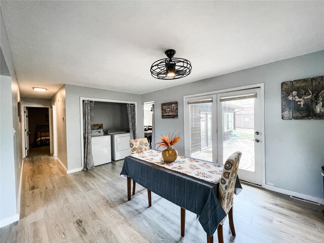 dining space featuring washing machine and clothes dryer, a textured ceiling, light wood finished floors, and baseboards