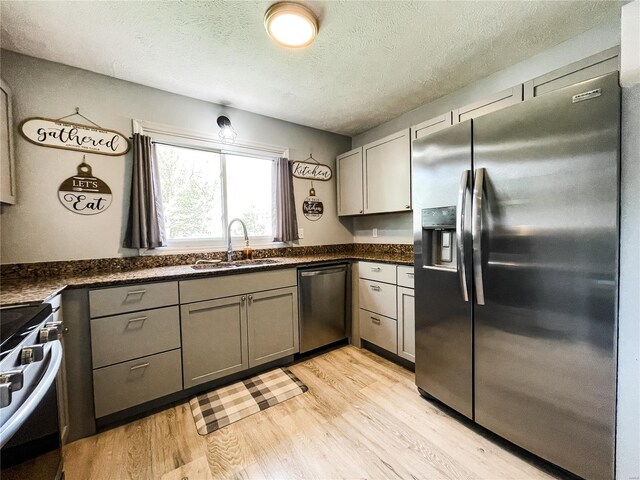 kitchen featuring light wood-style flooring, a sink, stainless steel appliances, and gray cabinetry