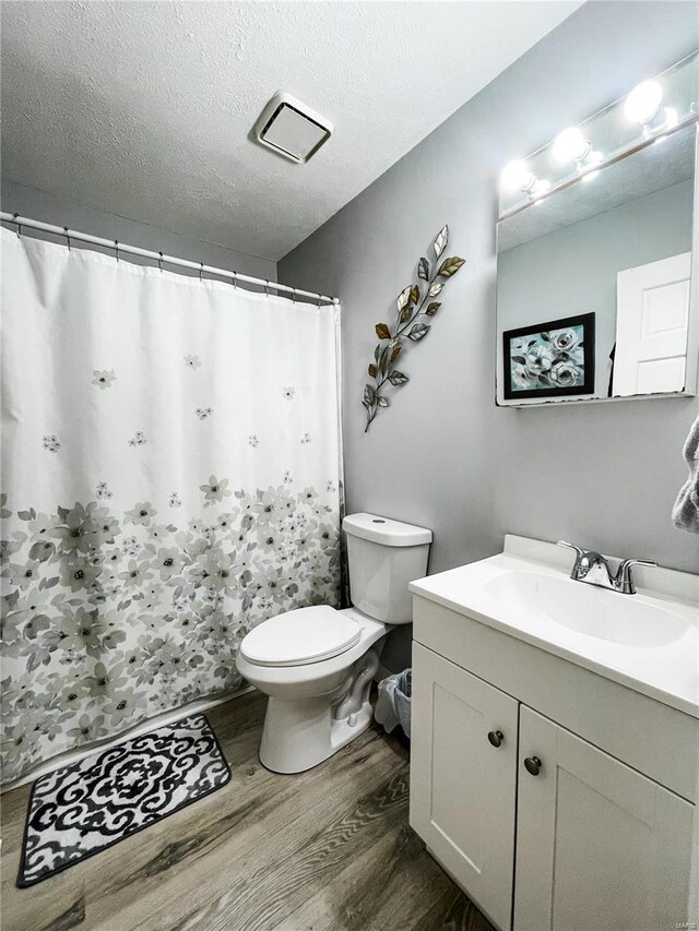 full bath featuring wood finished floors, a textured ceiling, vanity, toilet, and a shower with shower curtain
