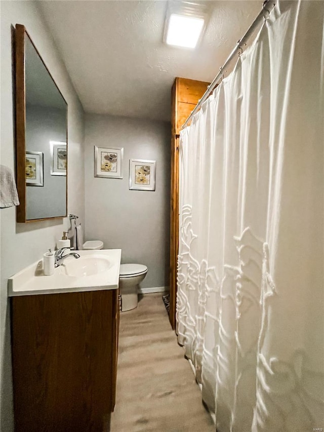 full bathroom featuring wood finished floors, vanity, a shower with curtain, baseboards, and toilet