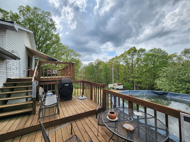 deck featuring stairs, outdoor dining space, a grill, and a covered pool