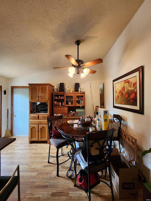 dining area featuring a textured ceiling, ceiling fan, and light wood-type flooring