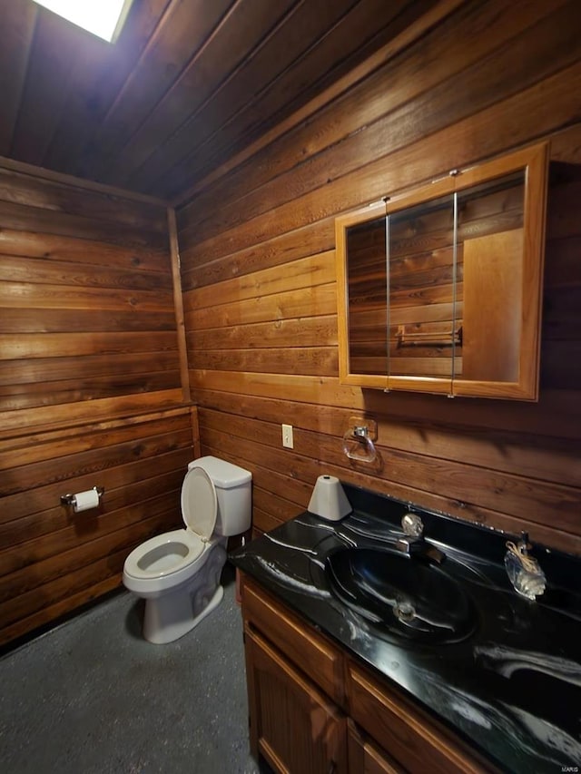 half bath featuring wooden walls, toilet, and vanity