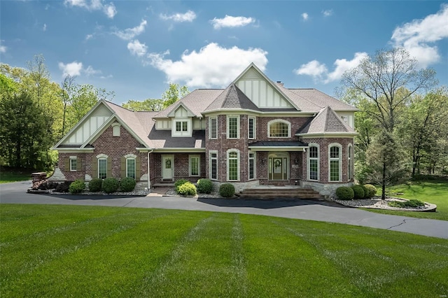 view of front of house with a front lawn, board and batten siding, and brick siding