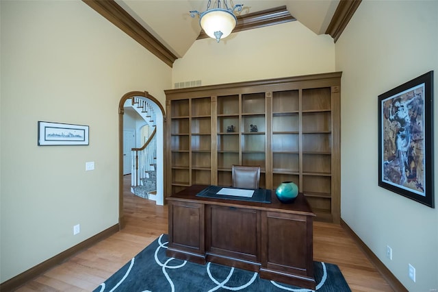 office space featuring visible vents, vaulted ceiling, baseboards, arched walkways, and wood finished floors