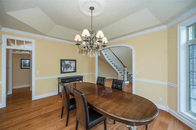 dining room featuring light wood finished floors, a chandelier, a raised ceiling, stairs, and baseboards
