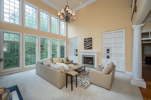 living room with decorative columns, built in shelves, a fireplace, and a high ceiling