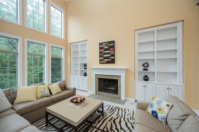 living area featuring a premium fireplace, a high ceiling, baseboards, and built in shelves