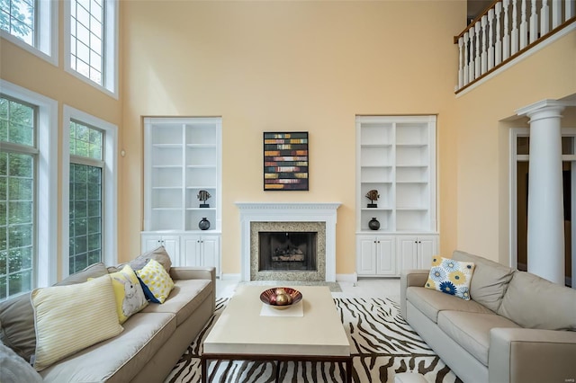 living area featuring a towering ceiling, a high end fireplace, and decorative columns
