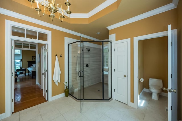 ensuite bathroom with a chandelier, toilet, a stall shower, baseboards, and ornamental molding