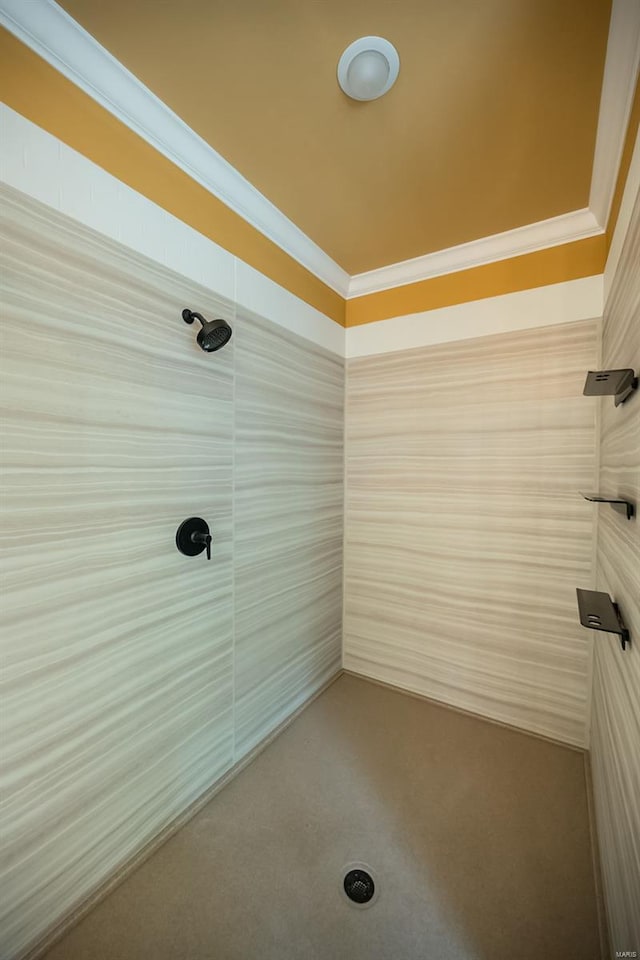 bathroom with ornamental molding and tiled shower