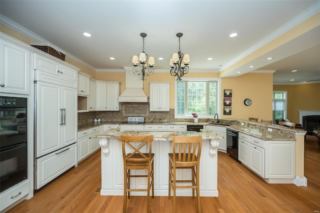 kitchen with a wealth of natural light, a chandelier, a peninsula, and dobule oven black