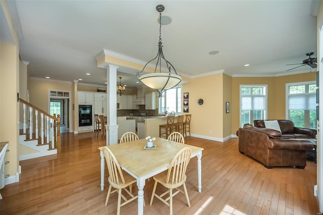 dining area featuring light wood-type flooring, ornamental molding, and decorative columns