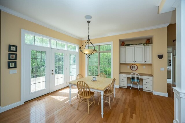 dining area with baseboards, light wood-type flooring, ornamental molding, and french doors
