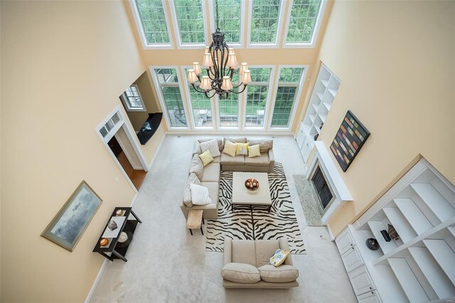 living room with a fireplace, a chandelier, baseboards, and a high ceiling