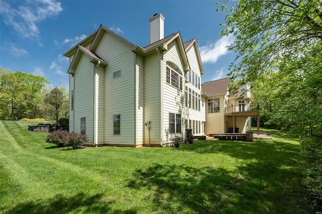 back of house featuring a chimney, a yard, and a wooden deck