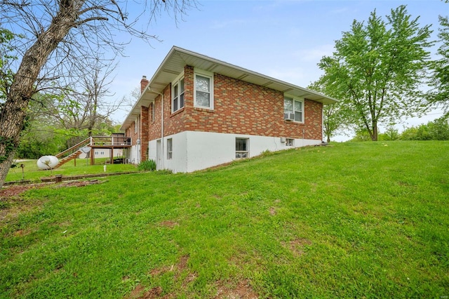 view of side of property with stairs, a chimney, brick siding, and a lawn