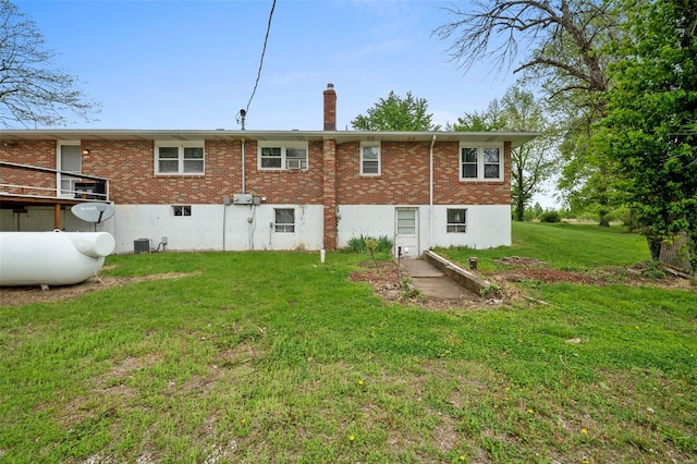 rear view of house with brick siding, a chimney, and a lawn