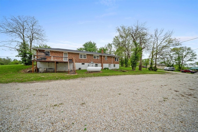 rear view of property with stairway, a wooden deck, a yard, and brick siding
