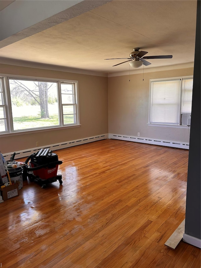 unfurnished room with a baseboard radiator, ceiling fan, and wood finished floors