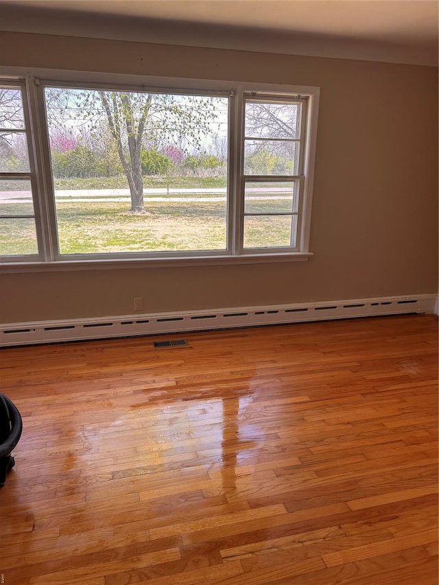 unfurnished room featuring baseboard heating and wood finished floors