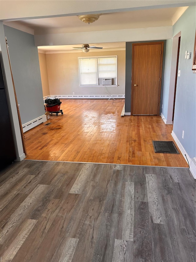 unfurnished room with a baseboard radiator, a ceiling fan, baseboards, wood finished floors, and cooling unit