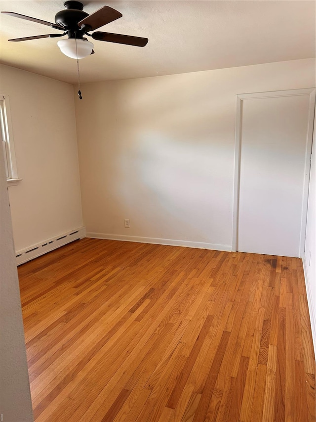 unfurnished room with a ceiling fan, a baseboard heating unit, light wood-style flooring, and baseboards