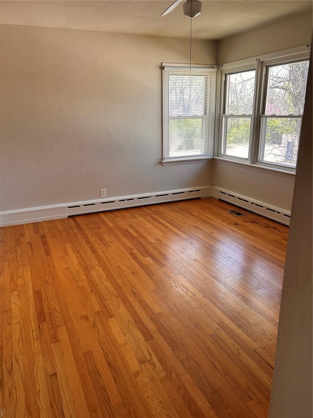 unfurnished room with light wood finished floors, a baseboard radiator, and baseboards