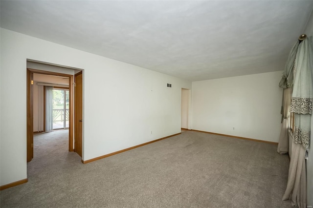 spare room featuring baseboards, visible vents, and carpet