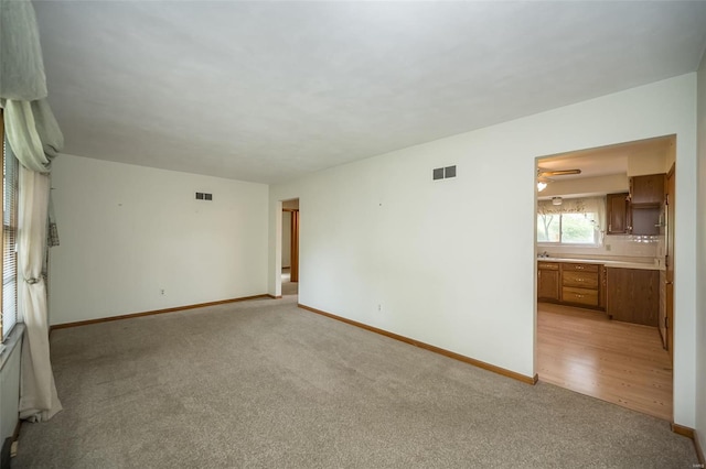 unfurnished room with visible vents, light colored carpet, and baseboards