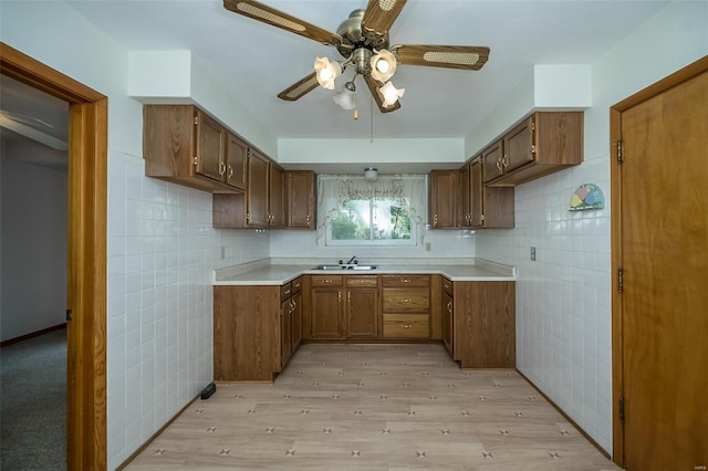 kitchen featuring tile walls, ceiling fan, light wood-style floors, and a sink