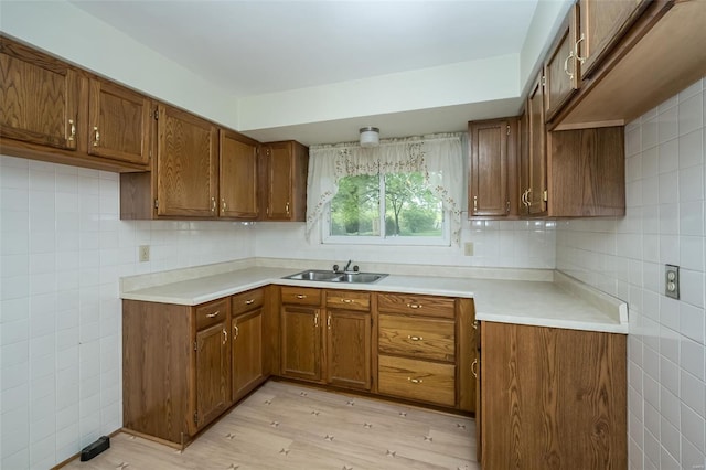kitchen featuring brown cabinets, light countertops, light wood-style flooring, and tile walls