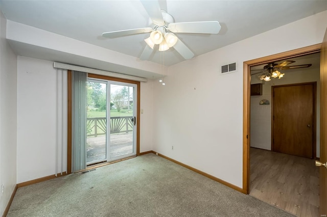 carpeted empty room with baseboards, visible vents, and a ceiling fan