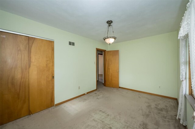 unfurnished bedroom featuring carpet floors, visible vents, a closet, and baseboards