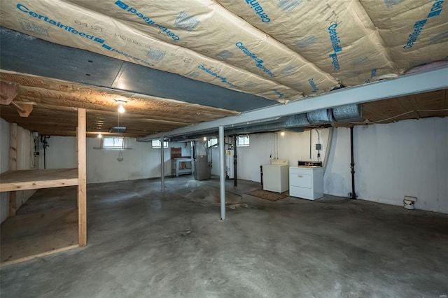 basement with heating unit, water heater, and washing machine and clothes dryer