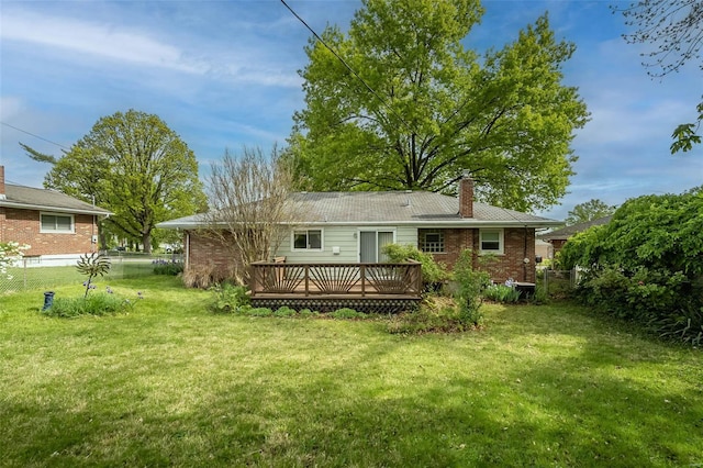 rear view of property featuring fence, a chimney, a yard, and a wooden deck