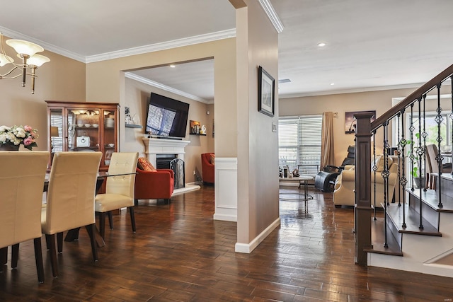 dining space with crown molding, a fireplace with raised hearth, stairs, and wood finished floors