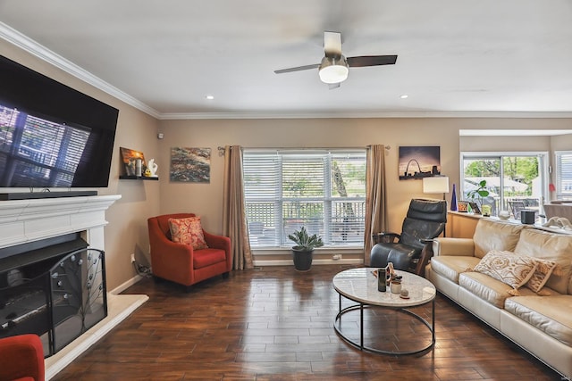 living area featuring ceiling fan, crown molding, hardwood / wood-style flooring, baseboards, and a fireplace with raised hearth