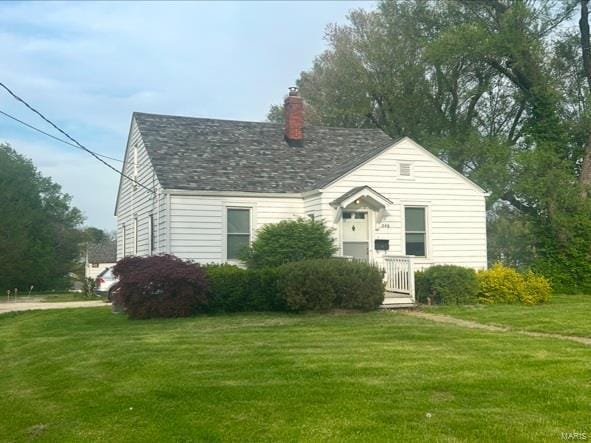view of front of home with a chimney and a front lawn