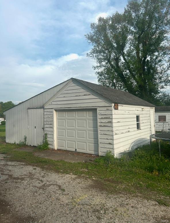 detached garage featuring a trampoline and dirt driveway