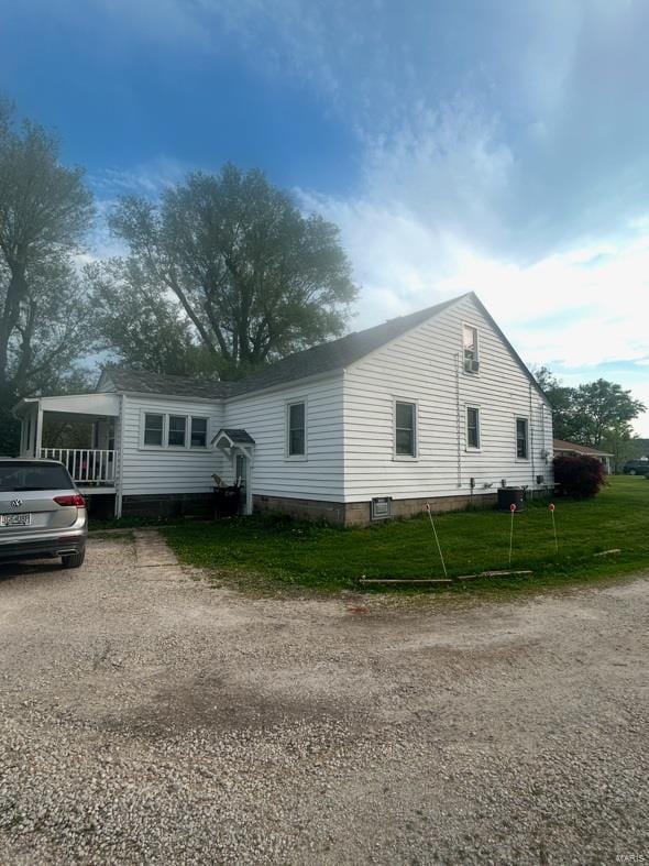 view of side of home featuring a lawn and dirt driveway