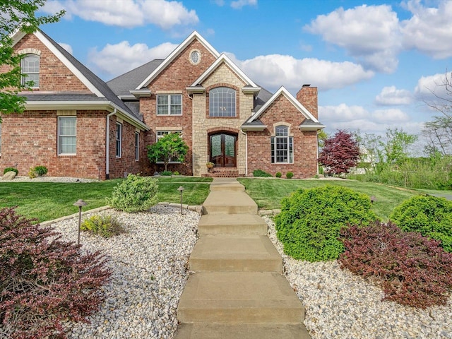 traditional-style home featuring a chimney, brick siding, and a front yard