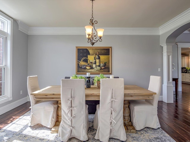 dining room featuring baseboards, arched walkways, ornamental molding, decorative columns, and wood finished floors