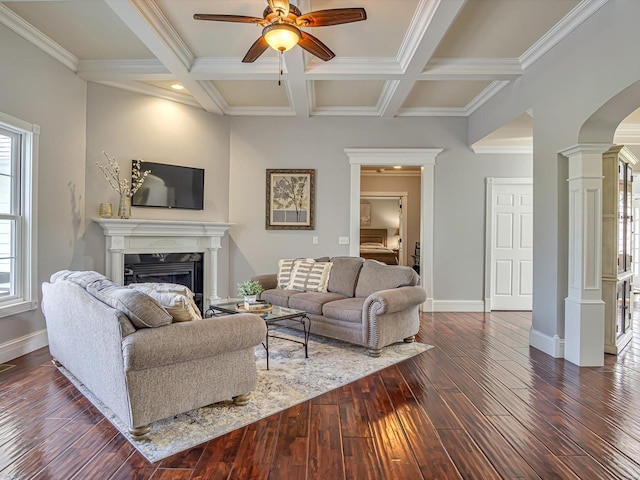 living area with dark wood-style floors, baseboards, a fireplace, ornate columns, and a ceiling fan