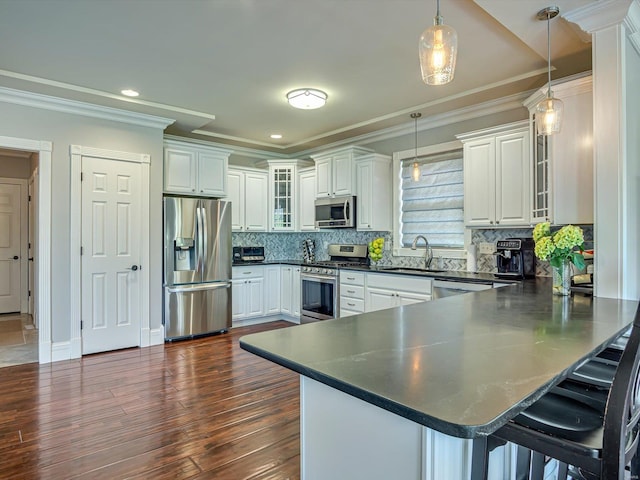 kitchen featuring white cabinets, glass insert cabinets, a sink, appliances with stainless steel finishes, and a peninsula