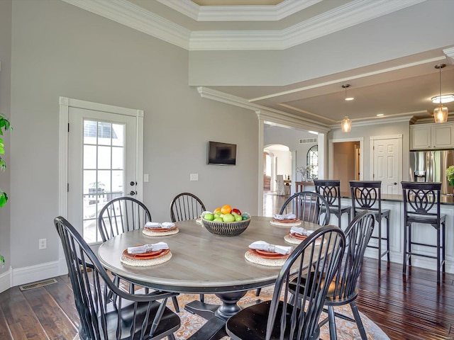 dining room featuring crown molding, visible vents, dark wood-style floors, baseboards, and arched walkways